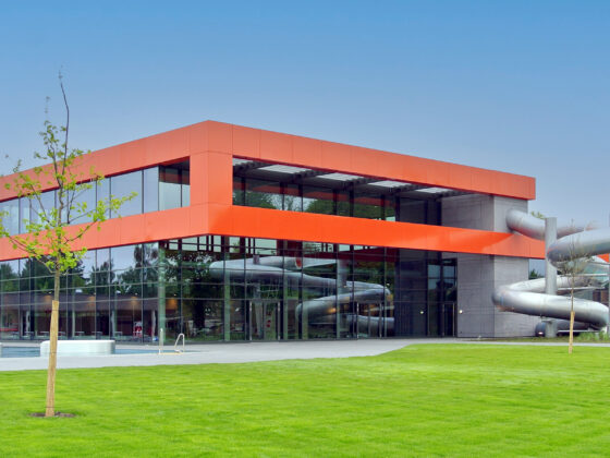 Moderne Architektur mit rotem Akzent und Wasserrutsche in einer grünen Umgebung.