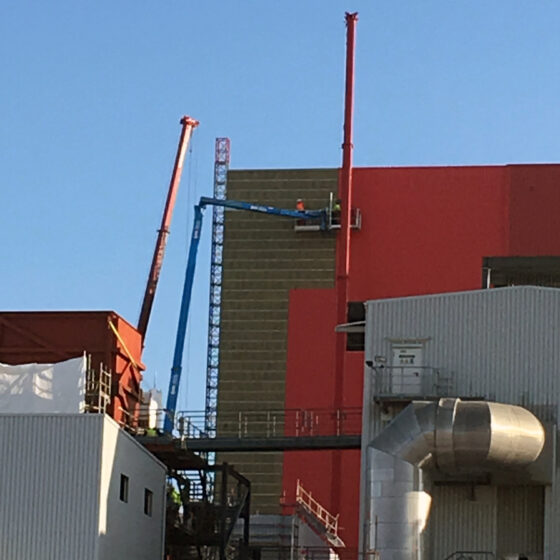 Bauarbeiter auf einem Gerüst bei Renovierungsarbeiten an einer Industrieanlage.