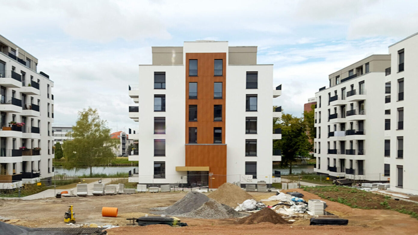 Bauplatz mit neuen Wohngebäuden und Baustellenmaterialien in urbaner Umgebung.