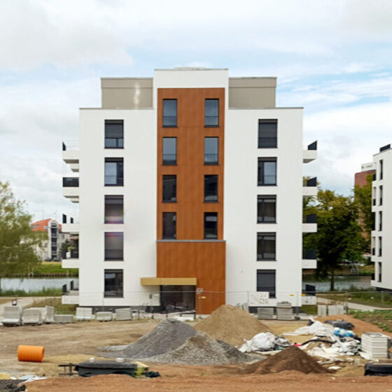 Bauplatz mit neuen Wohngebäuden und Baustellenmaterialien in urbaner Umgebung.