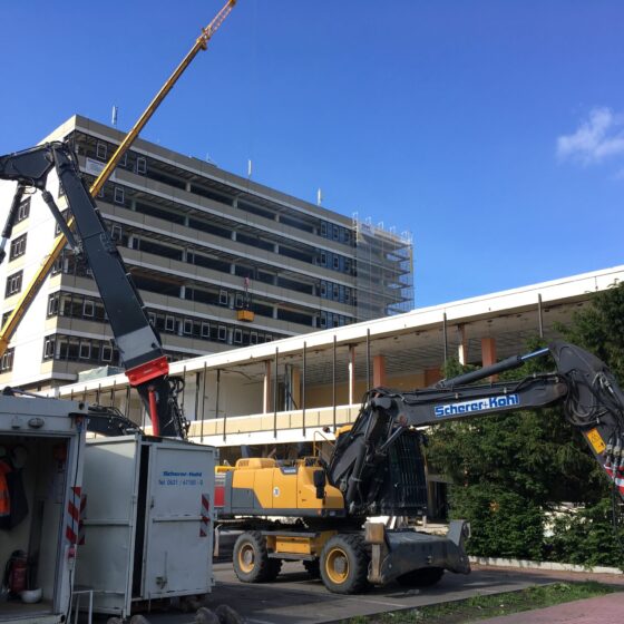 Bauarbeiten mit Kränen an einem mehrstöckigen Gebäude in urbaner Umgebung.