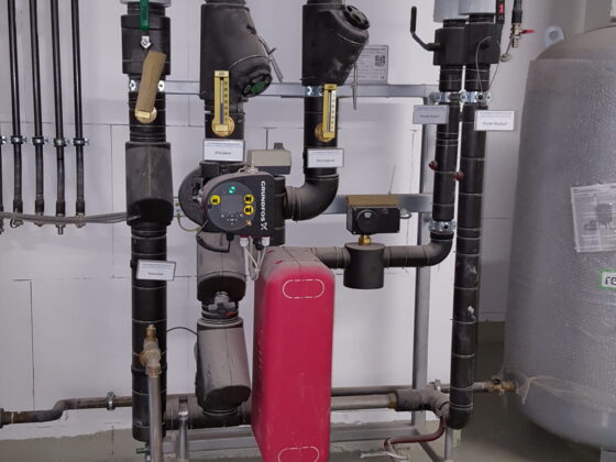 Technische Installation mit Rohren, Ventilen und einem Druckregler in einem modernen Gebäude.