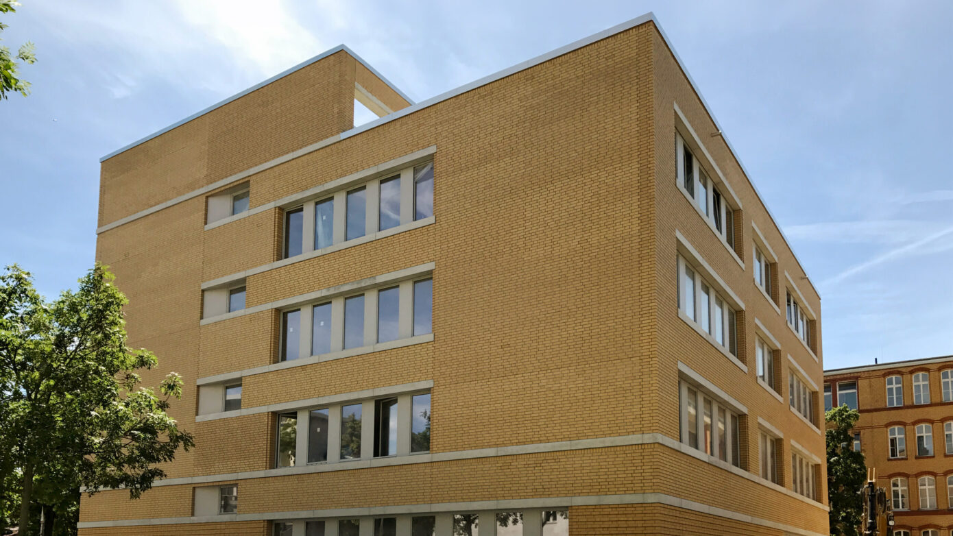 Kopernikus-Oberschule in Berlin mit moderner Architektur: Neubau mit hellen Ziegeln und großen Fenstern in städtischer Umgebung.