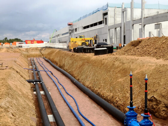 Bauarbeiten für die Logistikhalle in Hainichen mit Rohrleitungen und Maschinen auf einer Baustelle für ein neues Gebäude.