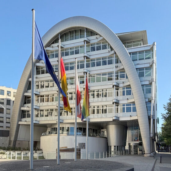 Ludwig Erhard Haus (IHK) mit moderner Architektur mit Flaggen vor blauen Himmel.