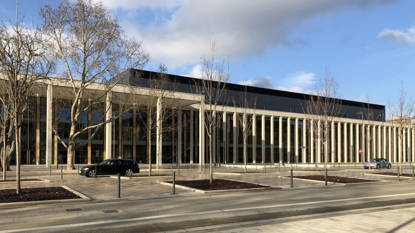 RheinMain CongressCenter Wiesbaden mit moderner Architektur mit Säulen und Glasfassade, umgeben von Bäumen und Straßen.