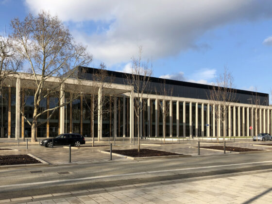 RheinMain CongressCenter Wiesbaden mit moderner Architektur mit Säulen und Glasfassade, umgeben von Bäumen und Straßen.