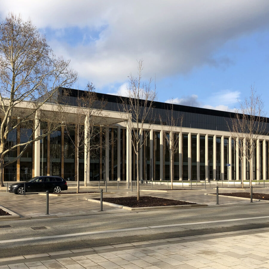 RheinMain CongressCenter Wiesbaden mit moderner Architektur mit Säulen und Glasfassade, umgeben von Bäumen und Straßen.