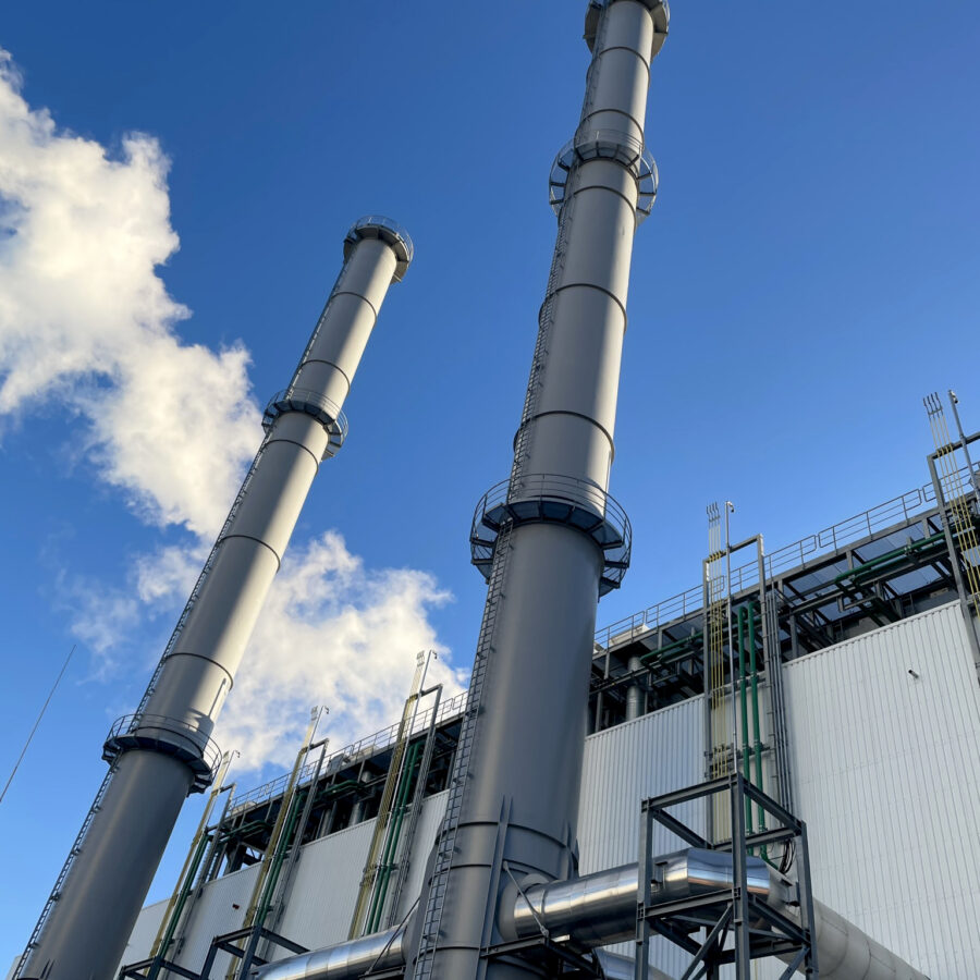 Blockheizkraftwerk Bremen Hastedt mit hohen Schornsteinen und blauem Himmel.