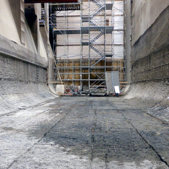 Blick in einen leeren Müllbunker mit Baugerüst an der hinteren Seite.