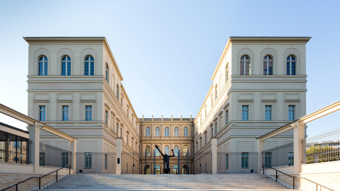 Museum Barberini mit Treppen und Skulptur, umgeben von klarem Himmel.