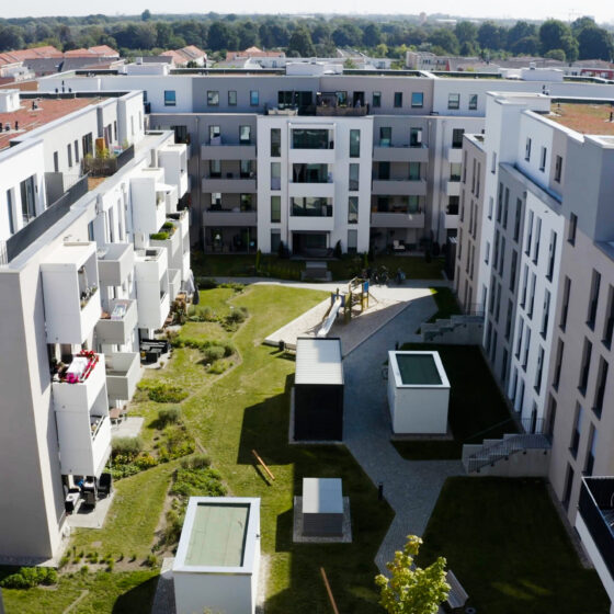 Moderne Wohnanlage mit Innenhof, Grünflächen und Spielplatz in urbaner Umgebung.