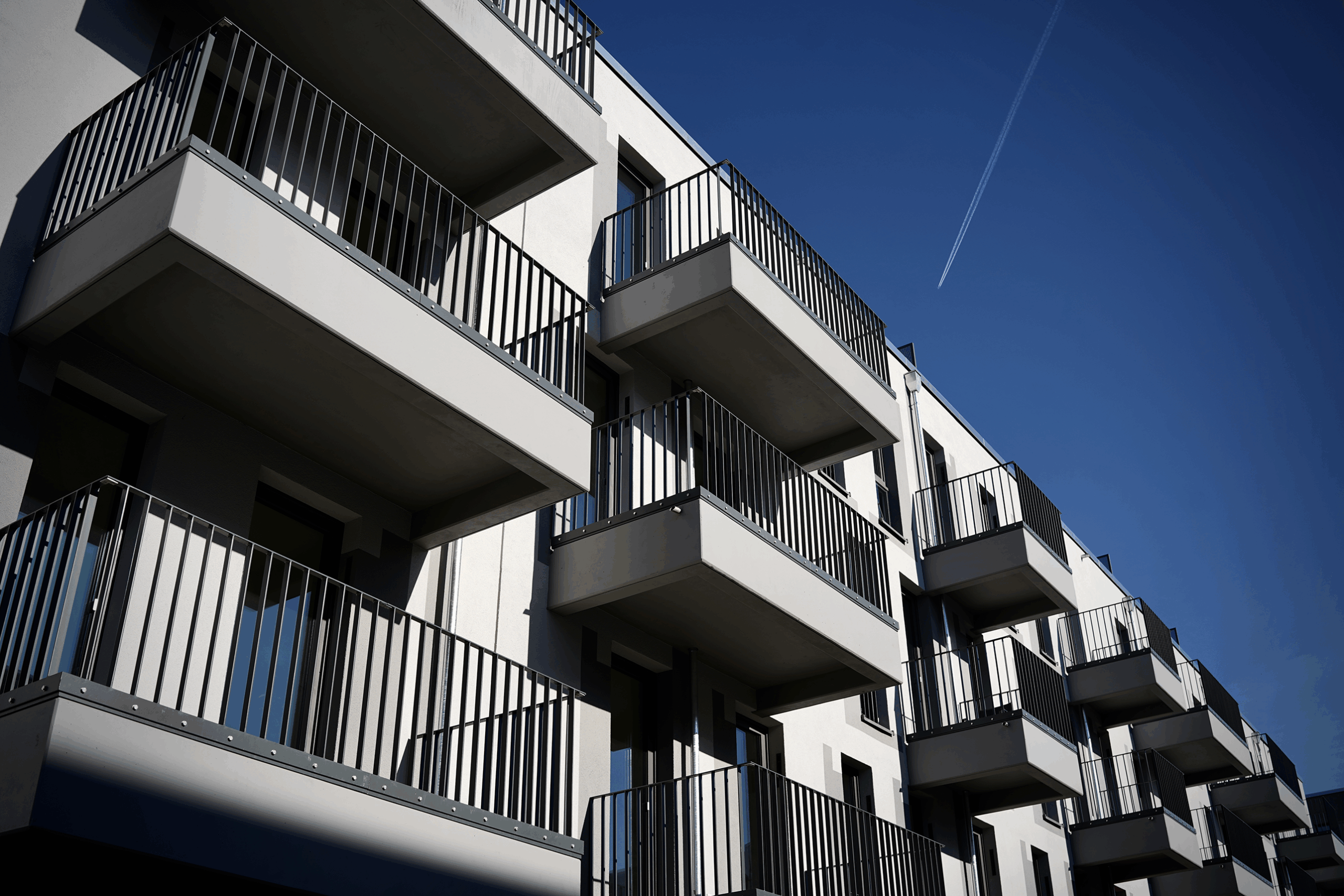 Moderne Wohnanlage mit Balkonen unter blauem Himmel und klarer Sicht.