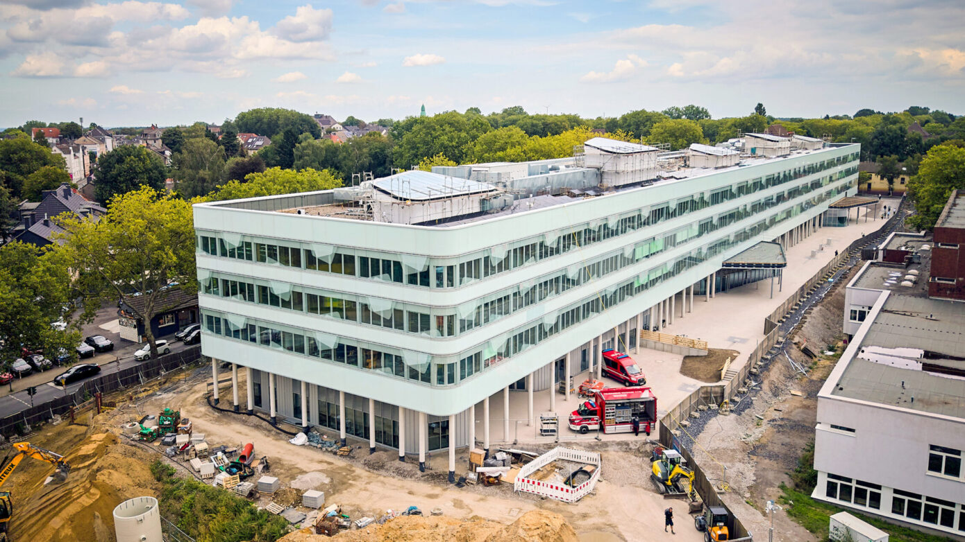 Ansicht des Schulzentrums Nord mit Baustelle in urbaner Umgebung.