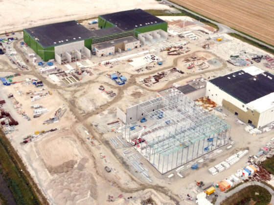 Luftaufnahme einer Baustelle mit mehreren Gebäuden und landwirtschaftlicher Umgebung.