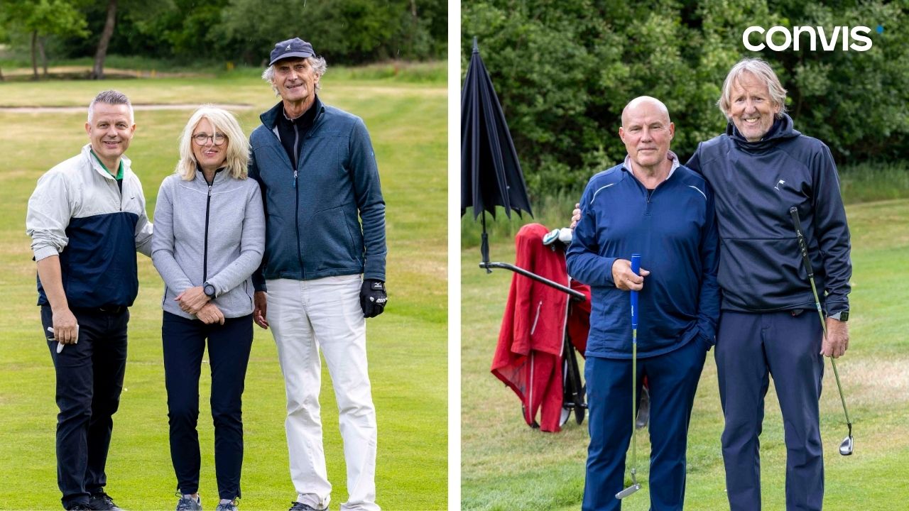 Golfspielende Gruppe auf dem Platz, lächelnd und gut gelaunt, mit Golfschlägern.