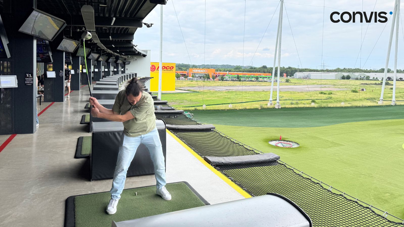 Mann beim Golftraining auf der Driving Range mit modernen Abschlagplätzen.
