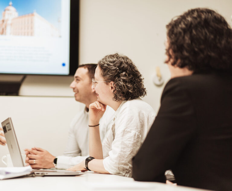 Teammeeting mit Präsentation: Mitarbeiter diskutieren und arbeiten gemeinsam an einem Laptop.