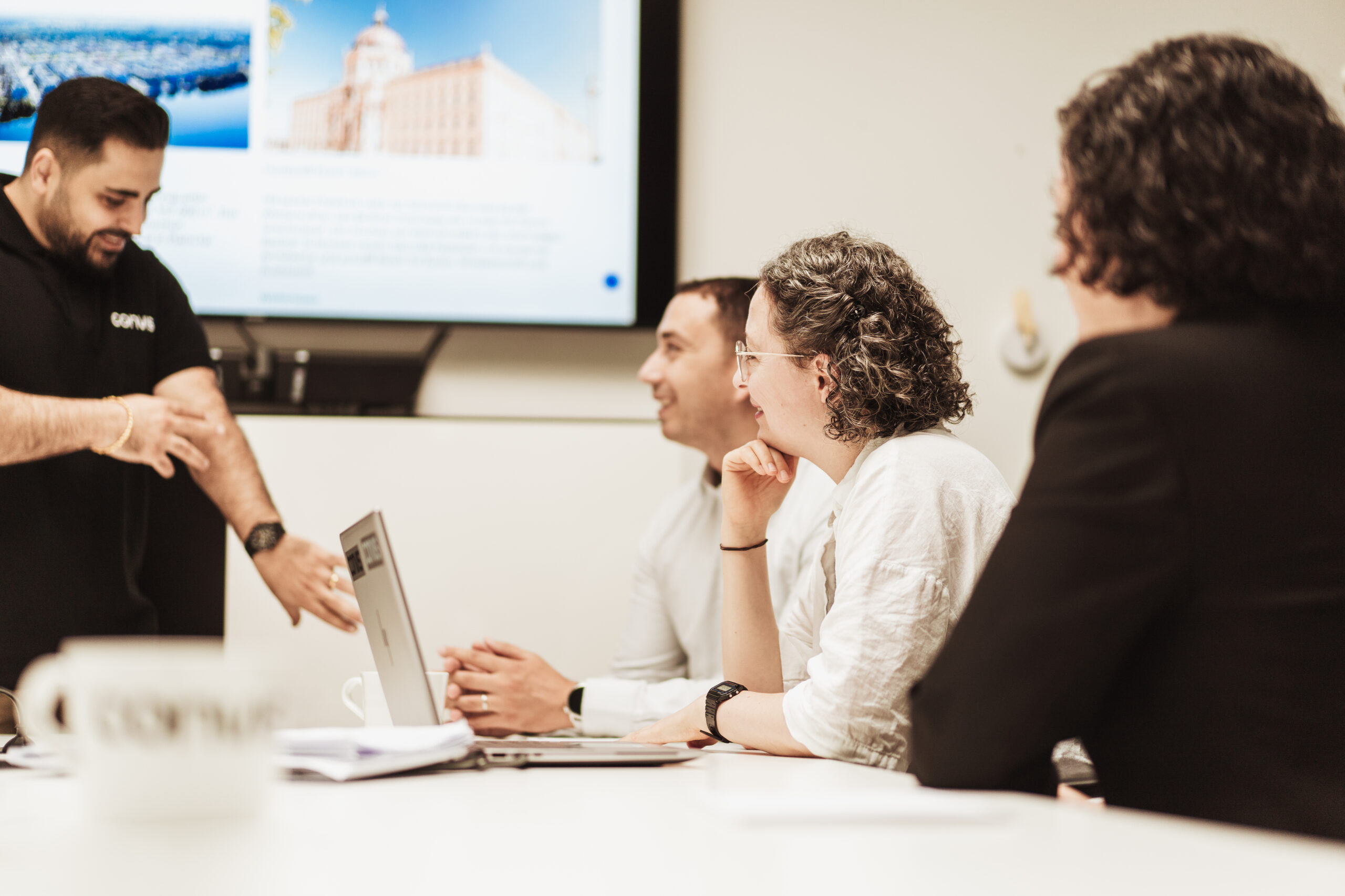 Teammeeting mit Präsentation: Mitarbeiter diskutieren und arbeiten gemeinsam an einem Laptop.