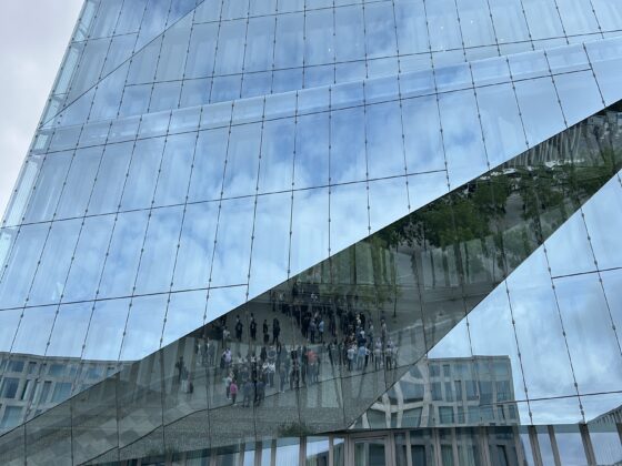 Moderne Glasarchitektur mit reflektierenden Oberflächen und Menschen im Vordergrund.