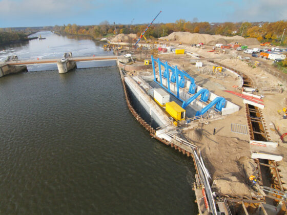 Bauarbeiten an einer Schleuse mit blauen Maschinen und Wasserweg im Hintergrund.