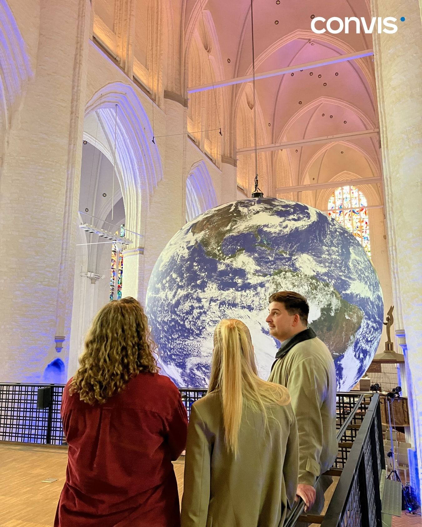 Besucher bewundern eine große Erdkugel in einer beeindruckenden Kirchenarchitektur.