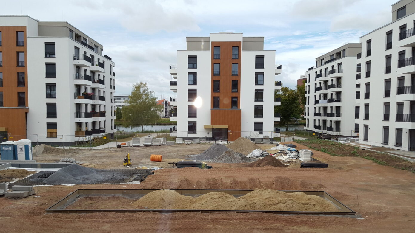 Bauprojekt mit modernen Wohngebäuden und Baustellenmaterialien in städtischer Umgebung.