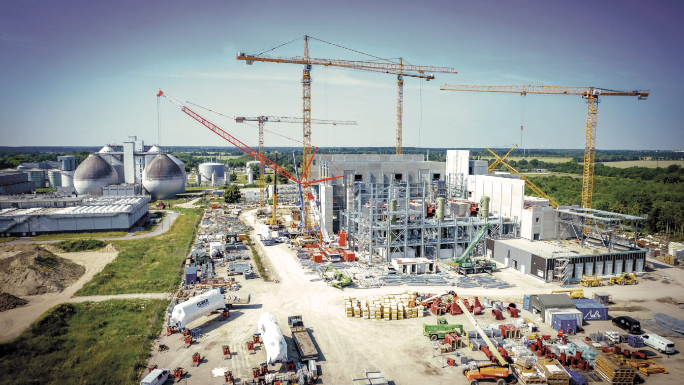 Bau einer modernen Industrieanlage mit Kränen und Lagerflächen in ländlicher Umgebung.