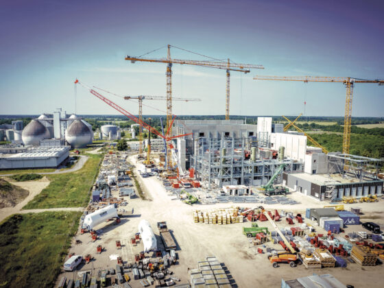 Bau einer modernen Industrieanlage mit Kränen und Lagerflächen in ländlicher Umgebung.