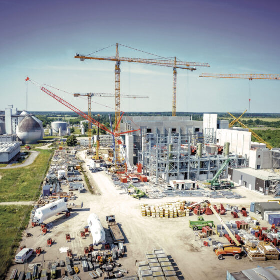 Bau einer modernen Industrieanlage mit Kränen und Lagerflächen in ländlicher Umgebung.