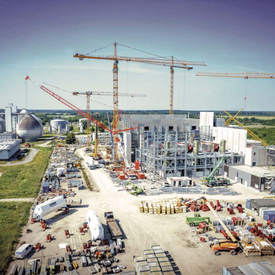 Bau einer modernen Industrieanlage mit Kränen und Lagerflächen in ländlicher Umgebung.