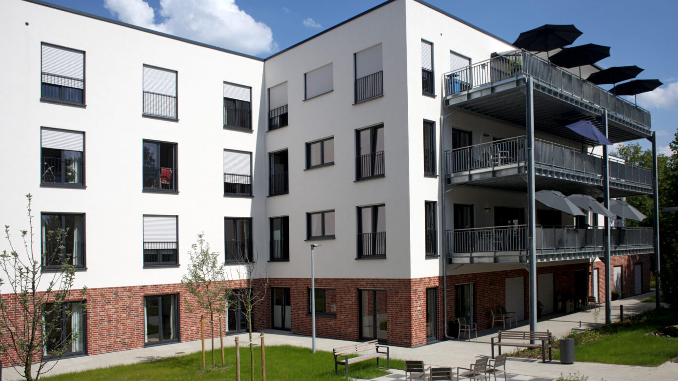 Moderne Wohnanlage mit Balkonen und grünem Innenhof, ideal für Familien.