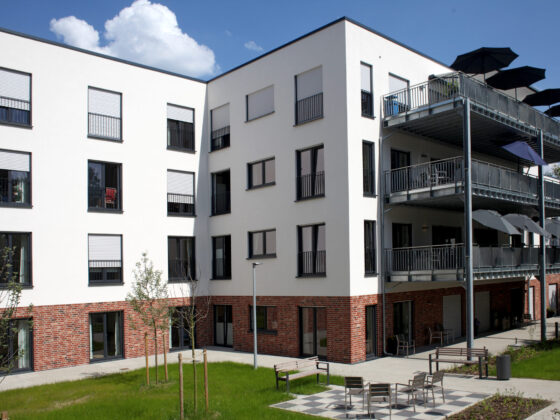 Moderne Wohnanlage mit Balkonen und grünem Innenhof, ideal für Familien.