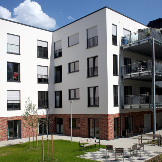 Moderne Wohnanlage mit Balkonen und grünem Innenhof, ideal für Familien.