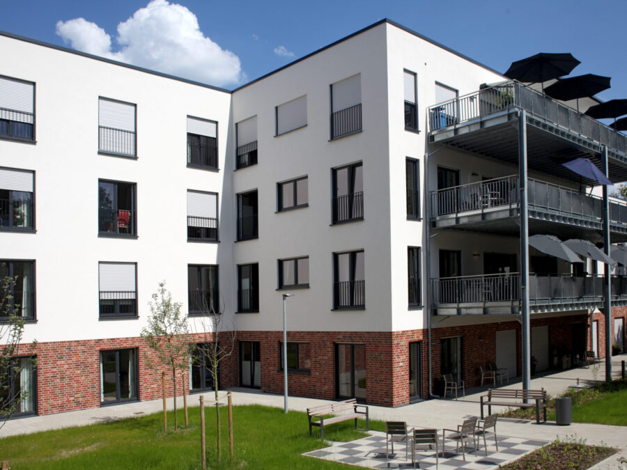 Moderne Wohnanlage mit Balkonen und grünem Innenhof, ideal für Familien.
