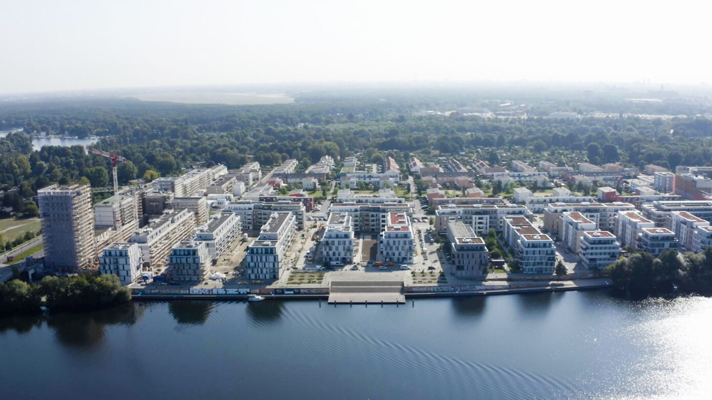 Moderne Wohnsiedlung am Wasser mit grünen Flächen und Bauprojekten in der Umgebung.