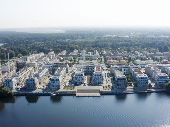 Moderne Wohnsiedlung am Wasser mit grünen Flächen und Bauprojekten in der Umgebung.