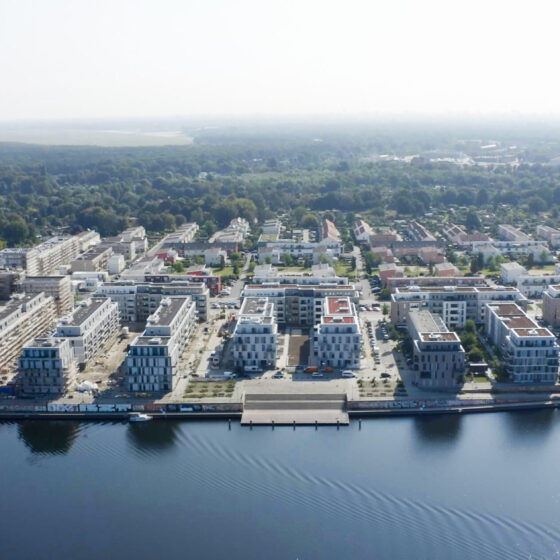 Moderne Wohnsiedlung am Wasser mit grünen Flächen und Bauprojekten in der Umgebung.