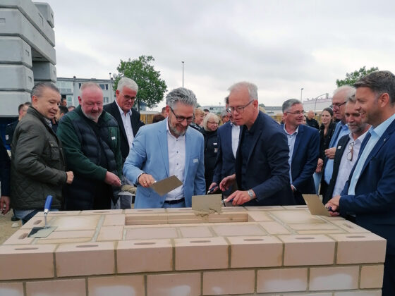 Grundsteinlegung mit mehreren Personen, die gemeinsam an einem Bauprojekt arbeiten.