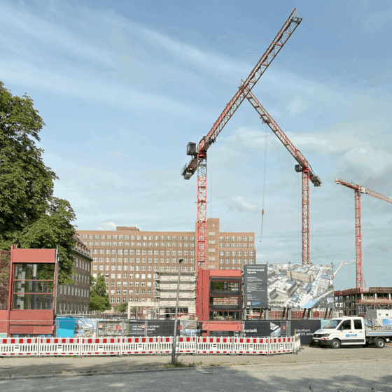 Bauprojekt mit Kränen und Baustelle, moderne Architektur und Umgebungsarbeiten in der Stadt.