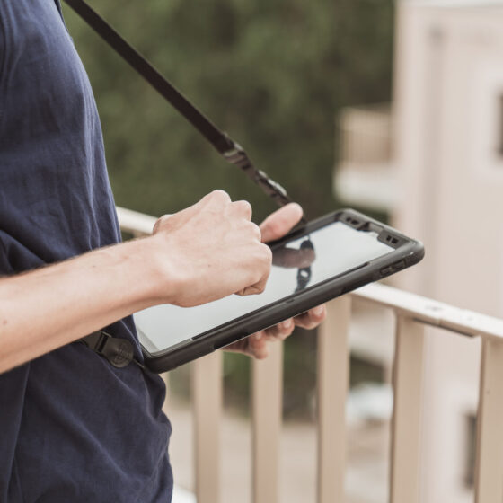 Person nutzt ein Tablet auf einem Balkon mit Stadtansicht.