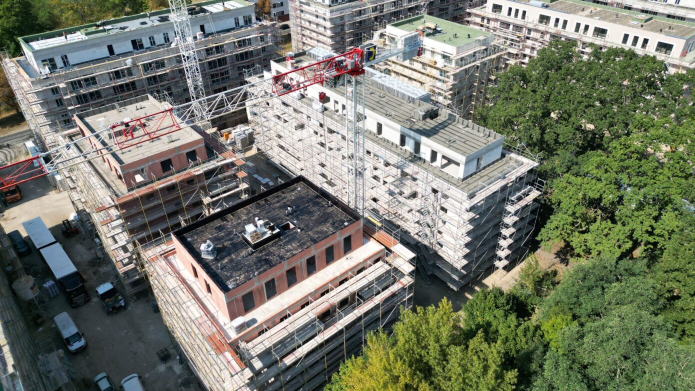 Bauarbeiten an modernen Wohngebäuden mit Gerüsten und Kränen in städtischer Umgebung.