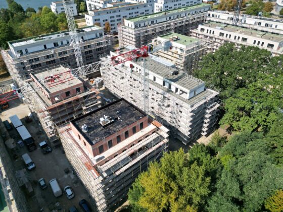 Bauarbeiten an modernen Wohngebäuden mit Gerüsten und Kränen in städtischer Umgebung.