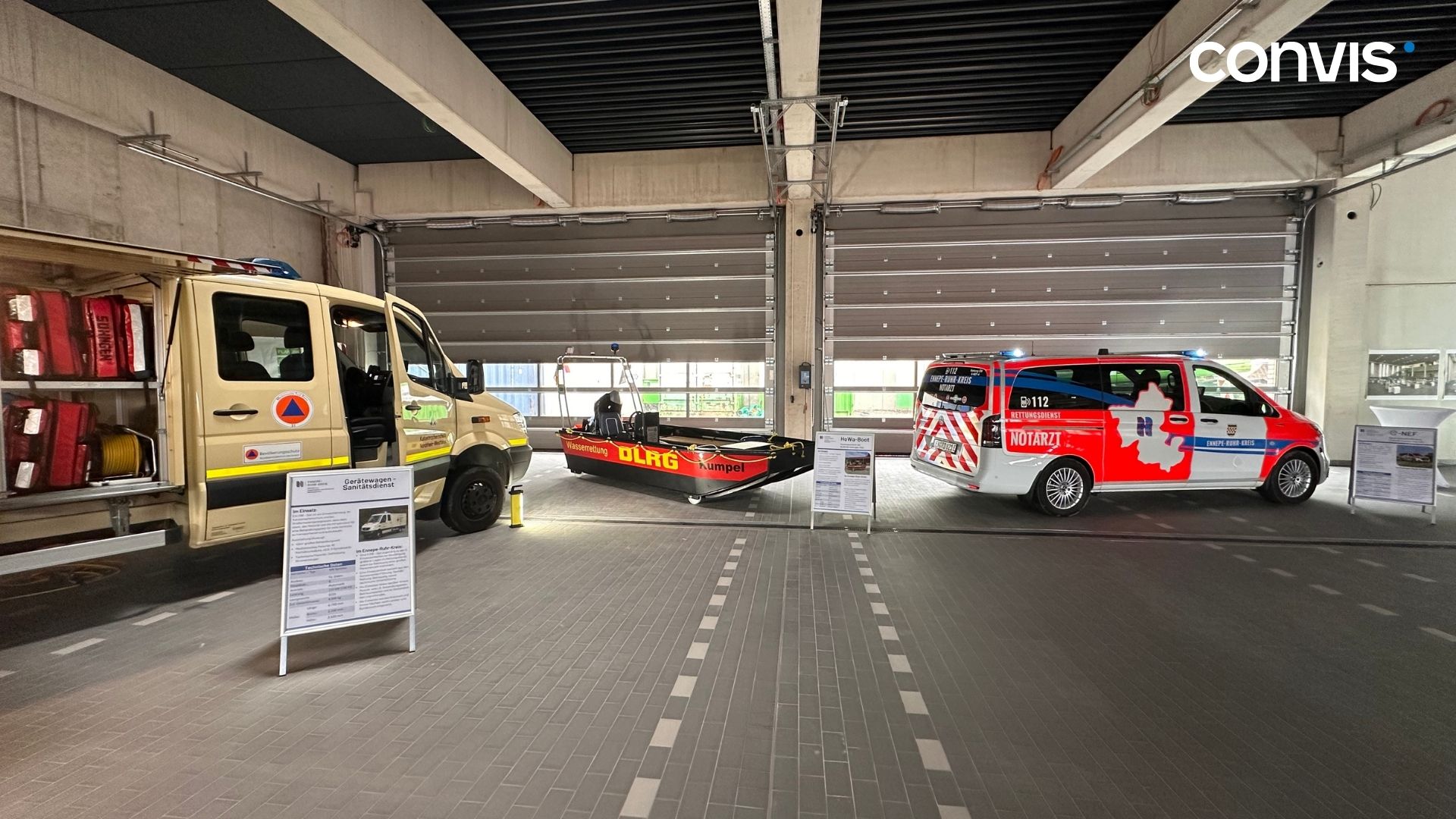 Rettungsfahrzeuge der DLRG und Feuerwehr in einer modernen Fahrzeughalle.