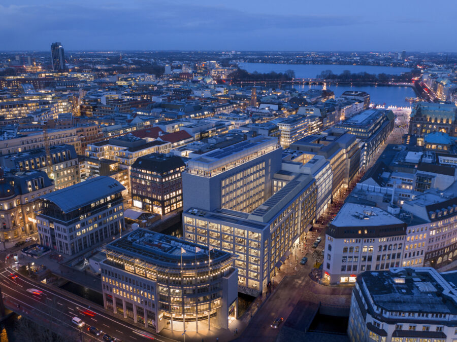 Luftaufnahme von Hamburg bei Nacht mit beleuchteten Gebäuden und Hafenansicht.