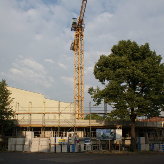 Bauprojekt mit Kran und Gerüst unter bewölktem Himmel in städtischer Umgebung.