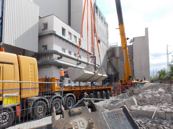 Bauarbeiten: Kranaushebung von Betonteilen auf einer Baustelle mit Abbrucharbeiten.