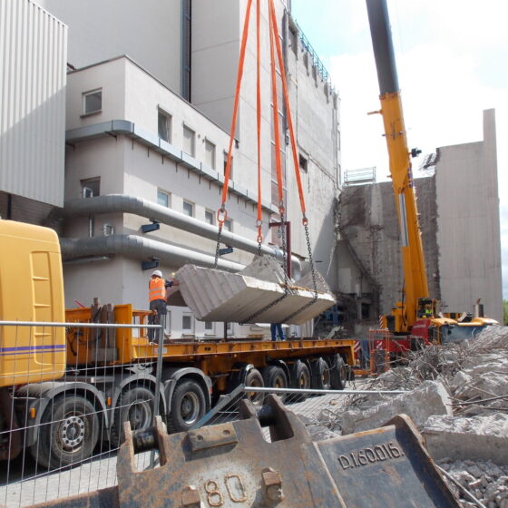 Bauarbeiten: Kranaushebung von Betonteilen auf einer Baustelle mit Abbrucharbeiten.