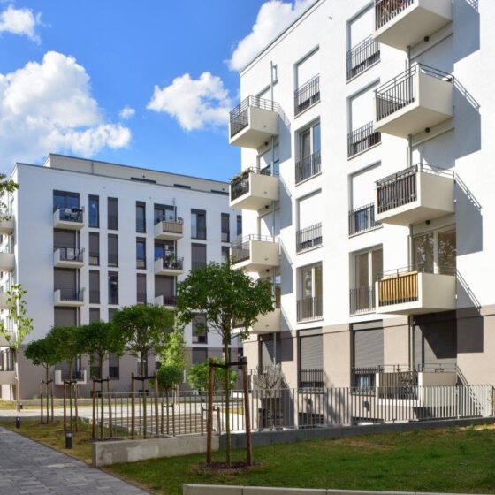 Moderne Wohnanlagen mit Balkonen und Grünflächen unter blauem Himmel.