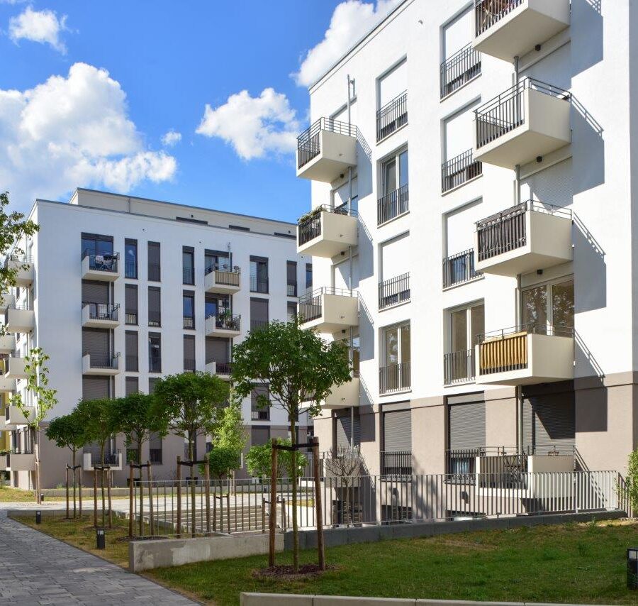Moderne Wohnanlagen mit Balkonen und Grünflächen unter blauem Himmel.